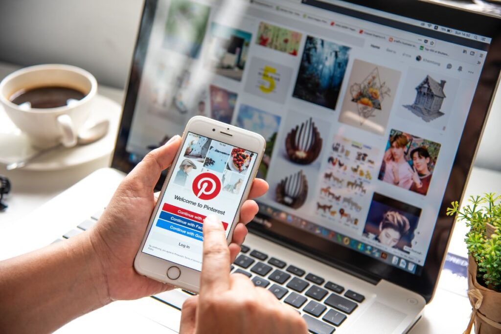 laptop of pinterest and someone holding a phone logging into pinterest